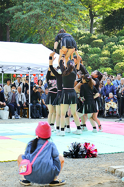 根津・千駄木下町祭りでの一コマ。女子学生のチアリーディングを真剣に、身動き一つしないで見詰める少女。